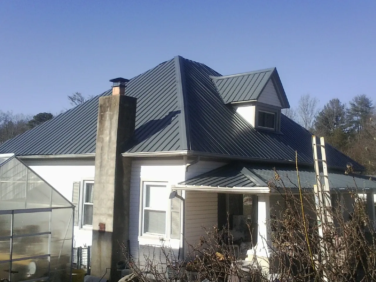 Dark blue standing seam metal roof on a white farmhouse with dormer — Slate & Tile Roof Repair by Roofing Brothers in Crystal Lake