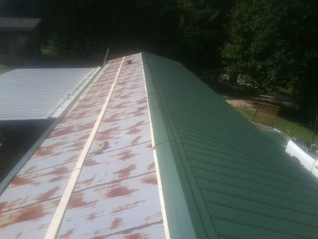 Old rusted panels beside newly installed green metal roofing — Wind Damage Roof Repair by Roofing Brothers in Crystal Lake