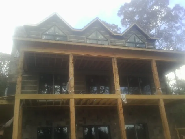 Dormers and porch framing on a large log home under construction — Roof Coating work by our crew in Crystal Lake