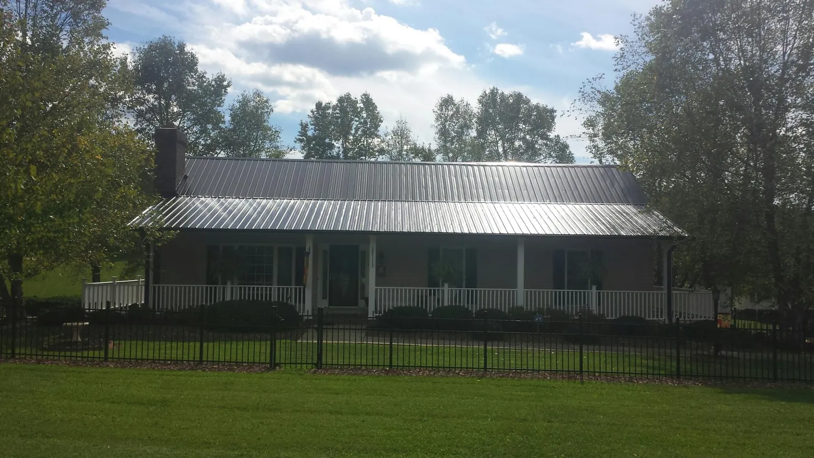 Gray metal roof on a brick ranch with a full width front porch — Gutter Guard Installation work by our crew in Crystal Lake