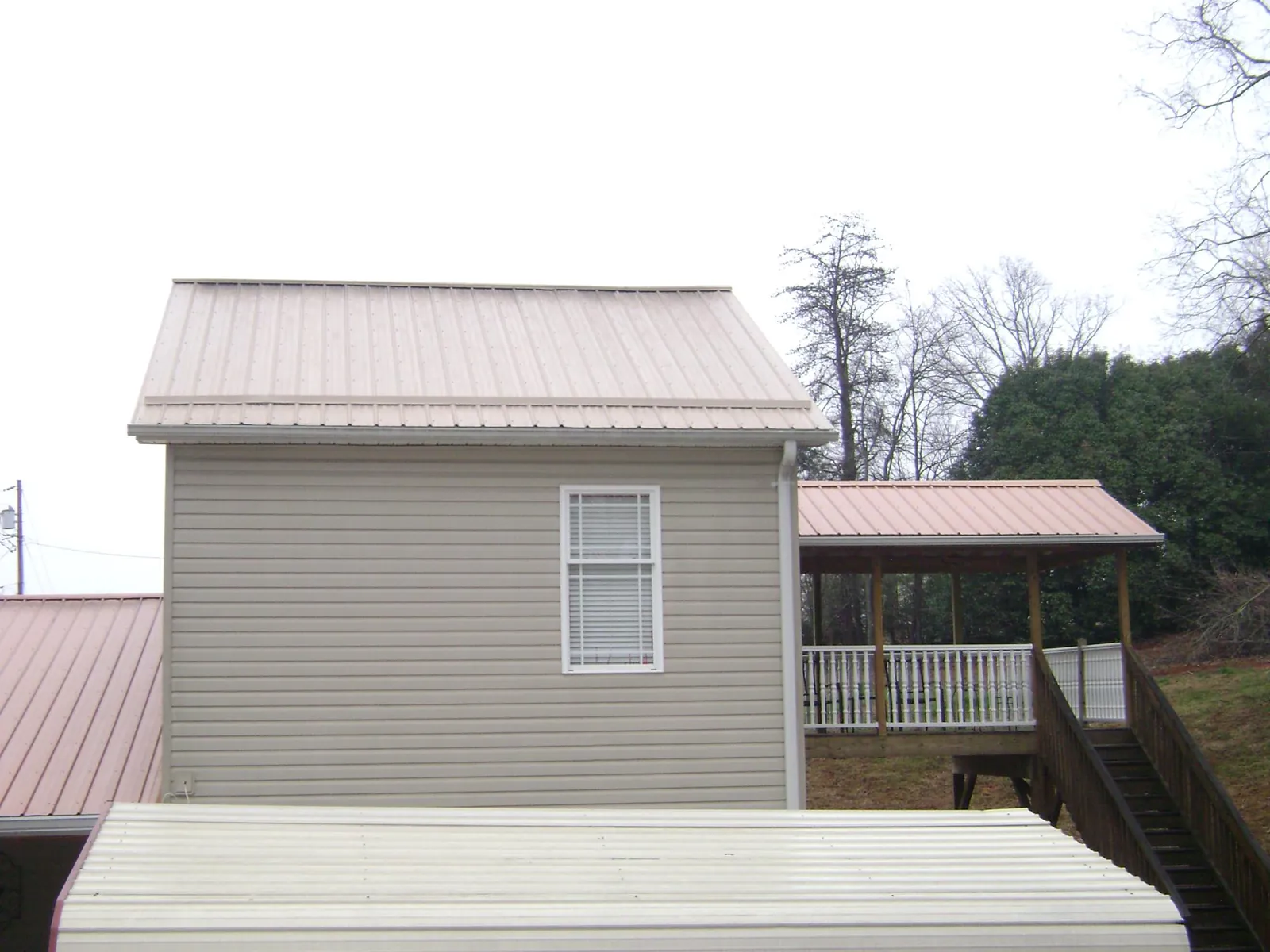 Tan metal roofs on a two story addition and attached porch, from a Roof Replacement job in Crystal Lake