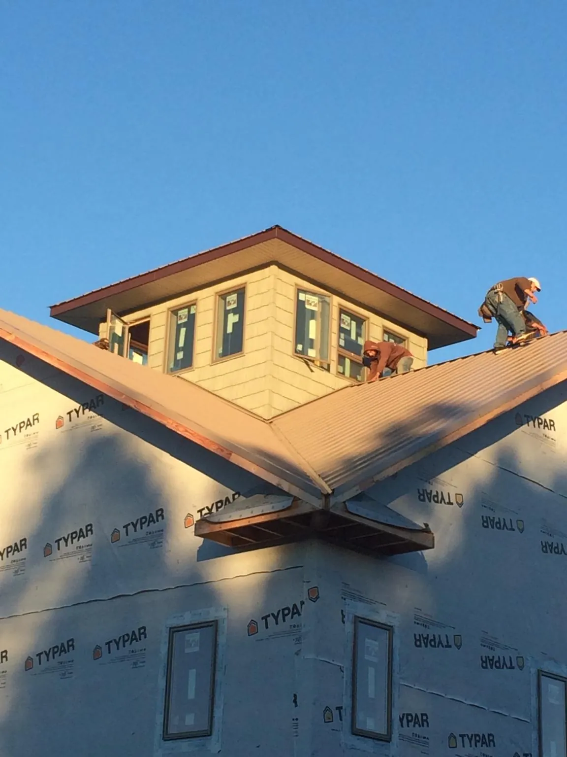 Roofers working around a rooftop cupola on a new metal roof at sunset — Roof Waterproofing in Crystal Lake by Roofing Brothers
